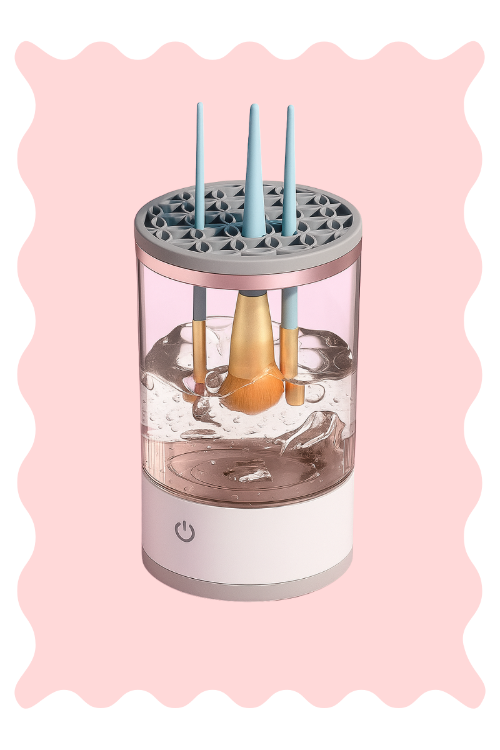 Nettoyeur USB Cleansette pour pinceaux de maquillage, appareil en fonctionnement avec brosse immergée dans l’eau sur fond rose.